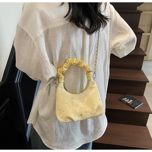 Detail of yellow pleated hobo bag with rhinestone embellishments and chain strap