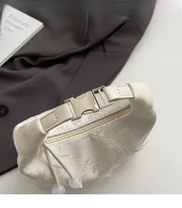 Close-up of white cloud bag featuring 3D floral embroidery and silver metal clasp