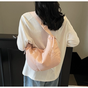 Detailed view of pink dumpling crossbody bag with pleats and adjustable strap on a model