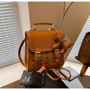 Detailed view of brown handbag featuring teddy bear print and logo metal clasp