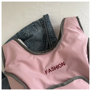 Detail of pink fashion vest featuring red letter embroidery and grey trim on fabric