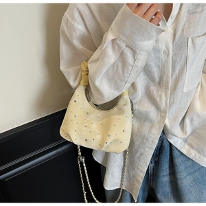 Detail of pleated dumpling bag with rhinestones, metal chain strap, and luxury leather texture