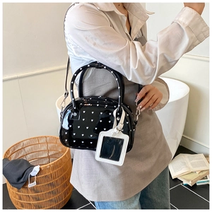 Dettaglio della borsa bowling in pelle verniciata nera con motivi a cuore bianco decorativi