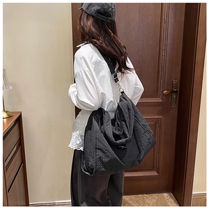 Detail of black and white checkered canvas tote bag with adjustable shoulder strap