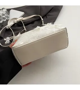 Detailed view of the flat bottom structure and delicate embroidery on this ivory handbag