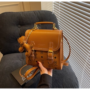 Detail of a brown leather vintage backpack with white stitching and cute cartoon bear patterns