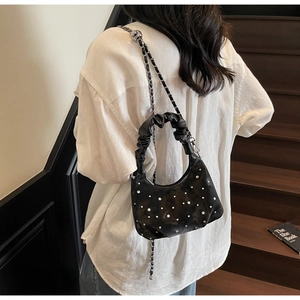 Detail of a black pleated half-moon bag featuring rhinestone decor and a silver chain strap