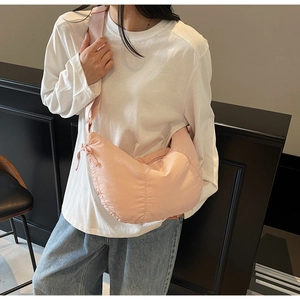 Detail of light pink nylon crescent bag with wide shoulder strap and soft pleats