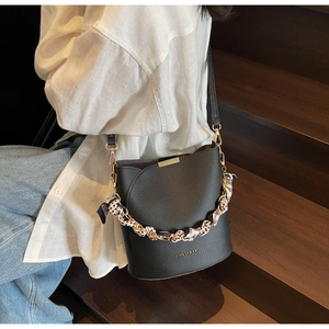 Detail of black pebbled leather bucket bag with leopard scarf and gold hardware accents
