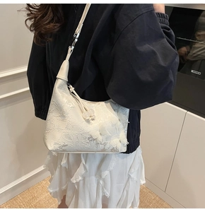 Detail of elegant cream-colored hobo bag with 3D lace flowers and embroidery texture