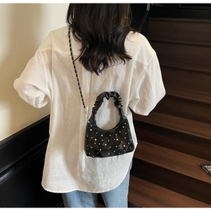 Detail of black dumpling bag with pearls, pleated handle, and chain strap for women