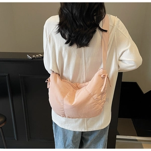 Detailed side view of pink dumpling bag showing fabric texture and bow tie knots