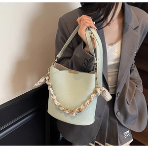 Detail of mint green lychee grain leather bucket bag with silk scarf chain and gold hardware