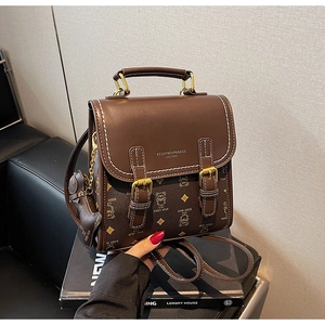 Close-up of vintage brown leather backpack featuring a bear pattern and gold metal buckle