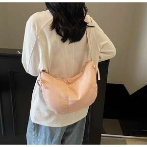 Pink crescent dumpling shoulder bag worn by model showing side profile and texture