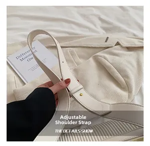 Detail view of adjustable shoulder strap with gold buckle on off-white pillow bag
