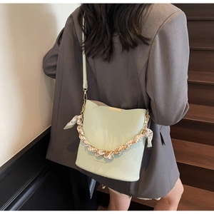 Detail of mint green bucket bag featuring lychee grain leather and silk scarf chain