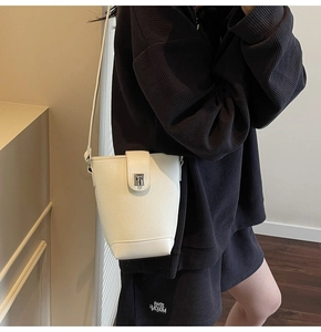 Detail of white lychee leather bucket bag with silver metal swivel lock and strap