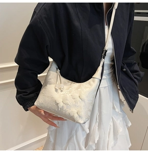 Détail d'un sac à main brodé blanc avec des fleurs en 3D et des motifs de papillons