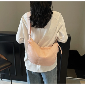 Pink crescent shoulder bag with pleated nylon texture and adjustable strap on model