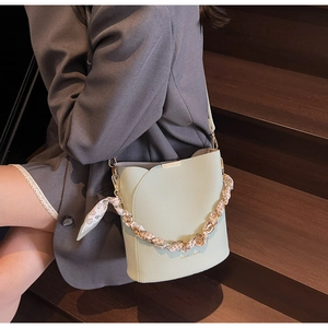 Detail of mint green bucket bag with lychee grain leather and decorative silk scarf