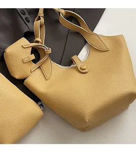 Close-up of mustard yellow bucket bag showing soft lychee grain leather and knot handle
