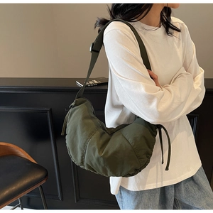 Detail of olive green crescent shoulder bag with drawstring texture and nylon fabric