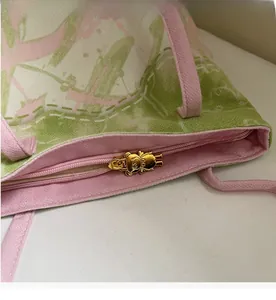 Detail of canvas tote bag showing metal bear-shaped zipper pull and smooth zip closure