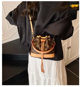 Detail view of vintage drawstring bucket bag with MQ pattern worn by a model