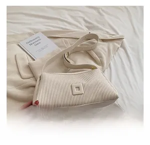 Detail of cream-colored pleated shoulder bag with adjustable strap and metal buckle