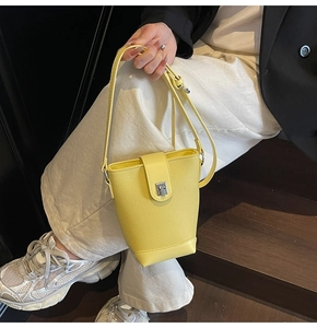 Close-up of yellow bucket bag with lychee texture and silver rotating metal lock