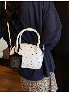 Glossy white bowling bag with heart patterns and crossbody strap shown on a model