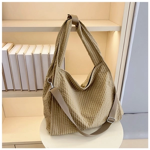 Detail of a beige gingham canvas tote bag with dual straps on a minimalist table