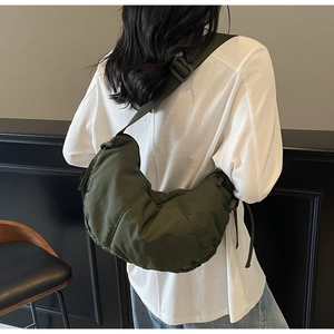 Detailed view of army green nylon crescent bag with adjustable strap on model back