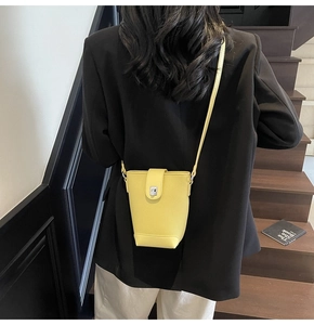Detail of yellow lychee grain leather bucket bag with silver metal clasp on black blazer