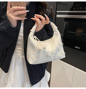 Détail du sac croissant en dentelle blanche avec fleurs d'organza 3D et perles