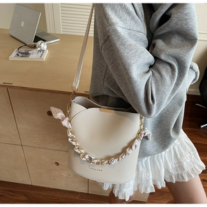 Detail of off-white bucket bag with lychee grain leather and silk scarf handle
