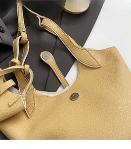 Close-up of yellow lychee-textured leather bucket bag with metal magnetic closure