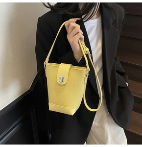Detail of yellow lychee leather bucket bag with silver buckle worn by a model