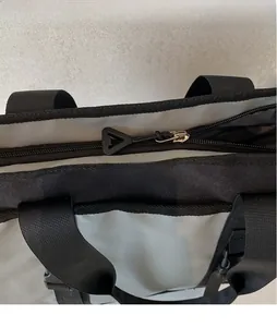 Close-up of modern gray and black crossbody bag showing extended zipper and nylon strap