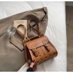 Detailed macro of brown leather teddy bear bag showing buckle straps and gold hardware