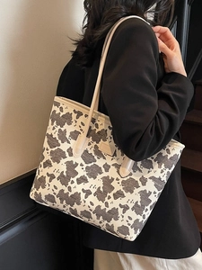Large capacity tote bag with black and white cow print and slim beige shoulder straps