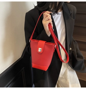 Detail of red leather bucket bag featuring silver turn-lock and pebbled texture