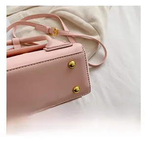 Close-up of the light pink PU leather bag bottom featuring four golden protective metal studs