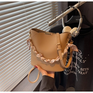 Detail of khaki bucket bag showing litchi grain texture and floral scarf chain handle