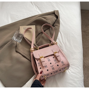Detailed view of pink crossbody bag with cartoon bear print and golden metal feet