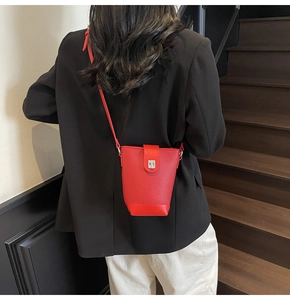 Detailed view of red pebble leather bucket bag with silver buckle worn by a model