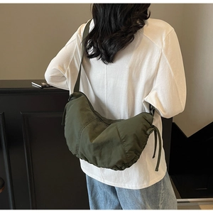 Detail view of deep green nylon crescent bag with drawstring side and wide shoulder strap
