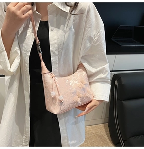 Détail d'un sac bandoulière rose avec motifs papillons 3D et broderies florales