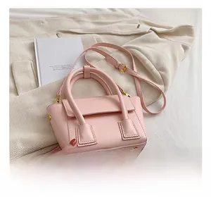 Detail of pink faux leather bucket bag with top handles and golden metal D-rings